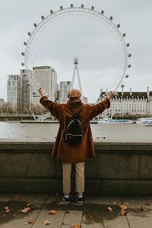 A tourist taking a photo of the London Eye, a giant Ferris wheel on the South Bank of the River Thames