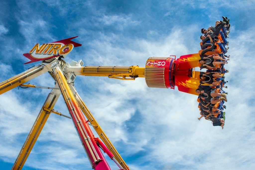 A joyous group of family and friends enjoying a sunny day at a vibrant English theme park, filled with exciting rides and attractions