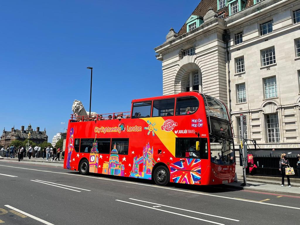 A bright red City Sightseeing London double-decker bus on a sunny day, offering one of the best London city bus tours with scenic views.